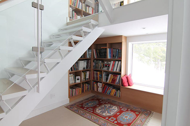 a glass staircase with bookshelves and a rug.