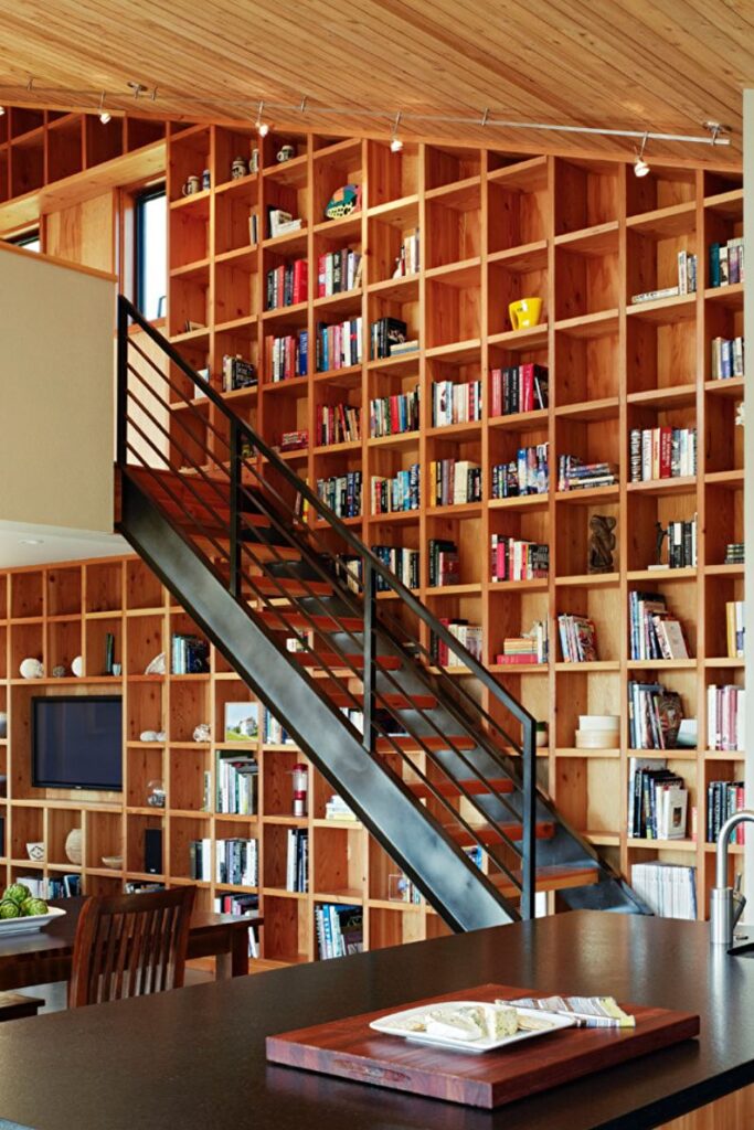 a living room with bookshelves and a staircase.