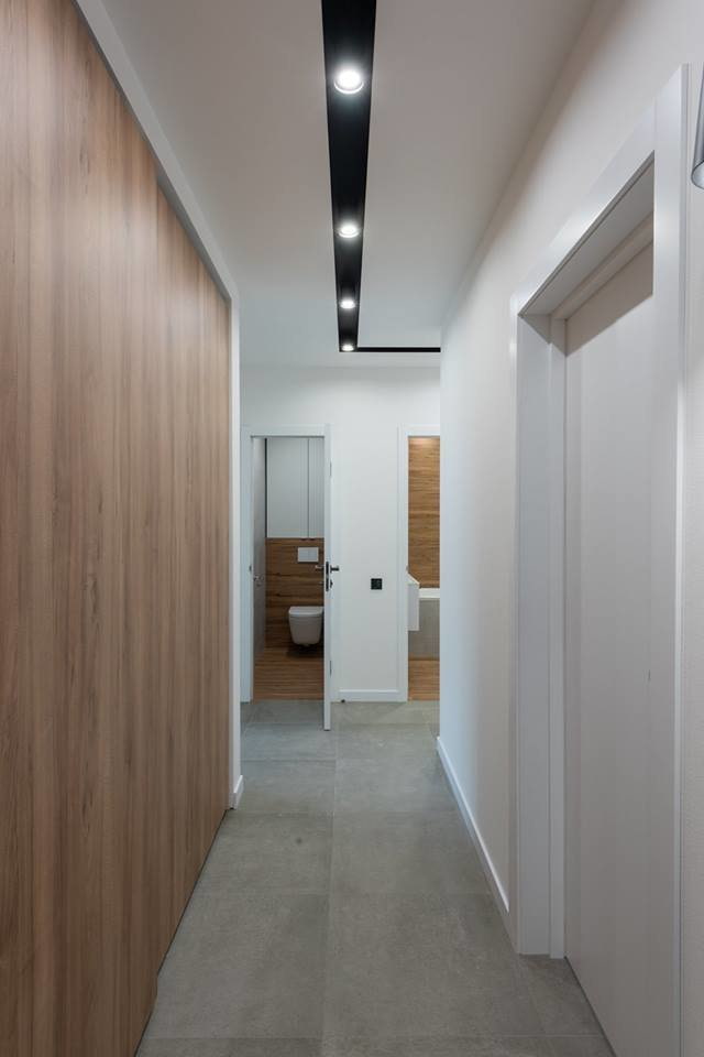 a hallway with a wooden floor and white walls.