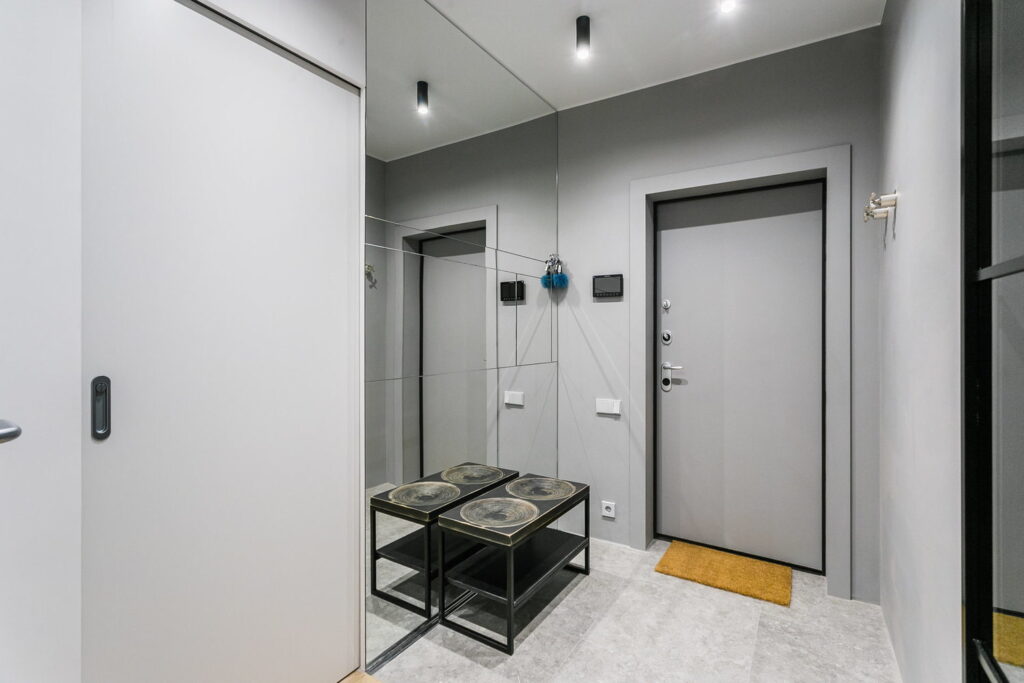 a hallway in a modern apartment with a mirror and a stool.