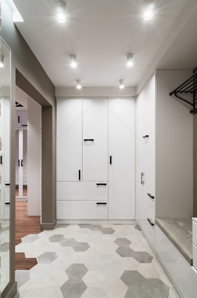 a walk in closet with white cabinets and a tiled floor.