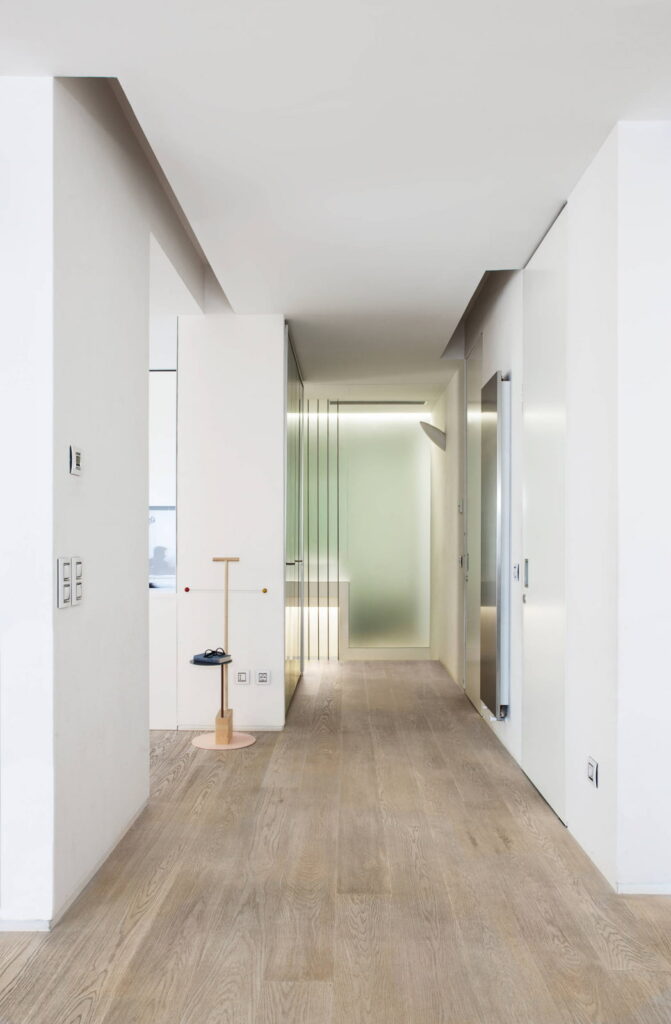 a hallway with white walls and wooden floors.