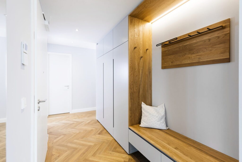 a hallway with a wooden bench and a coat rack.