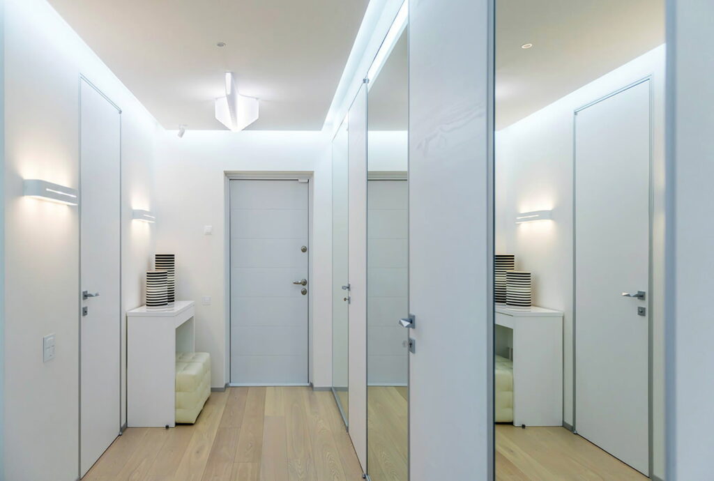 a hallway with white closets and mirrors.