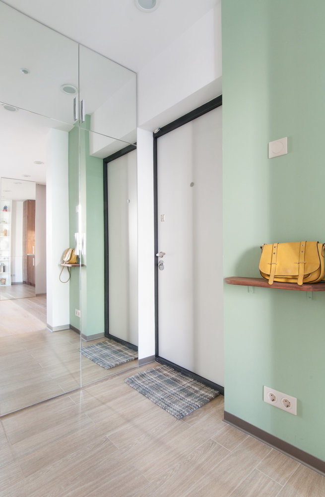 a hallway with green walls and a mirror.