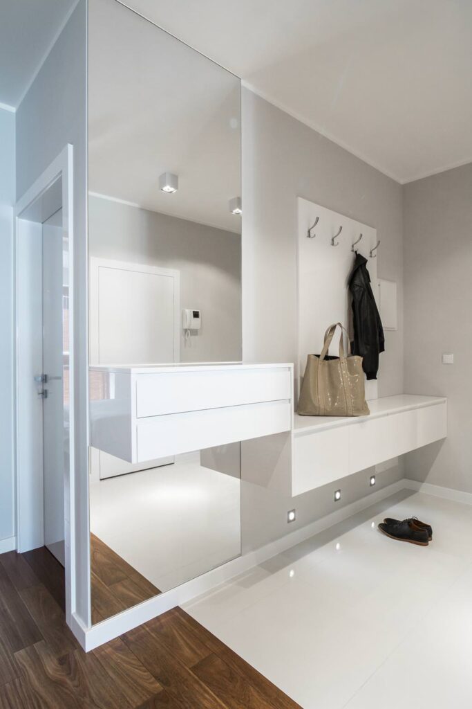 a white entryway with a coat rack and a bag.