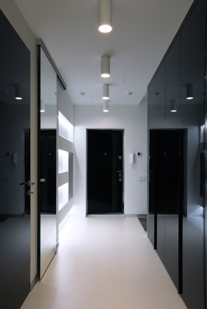 a hallway with black and white cabinets and mirrors.