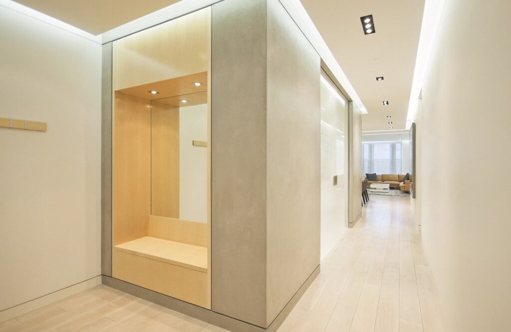 a hallway with a wooden bench and white walls.