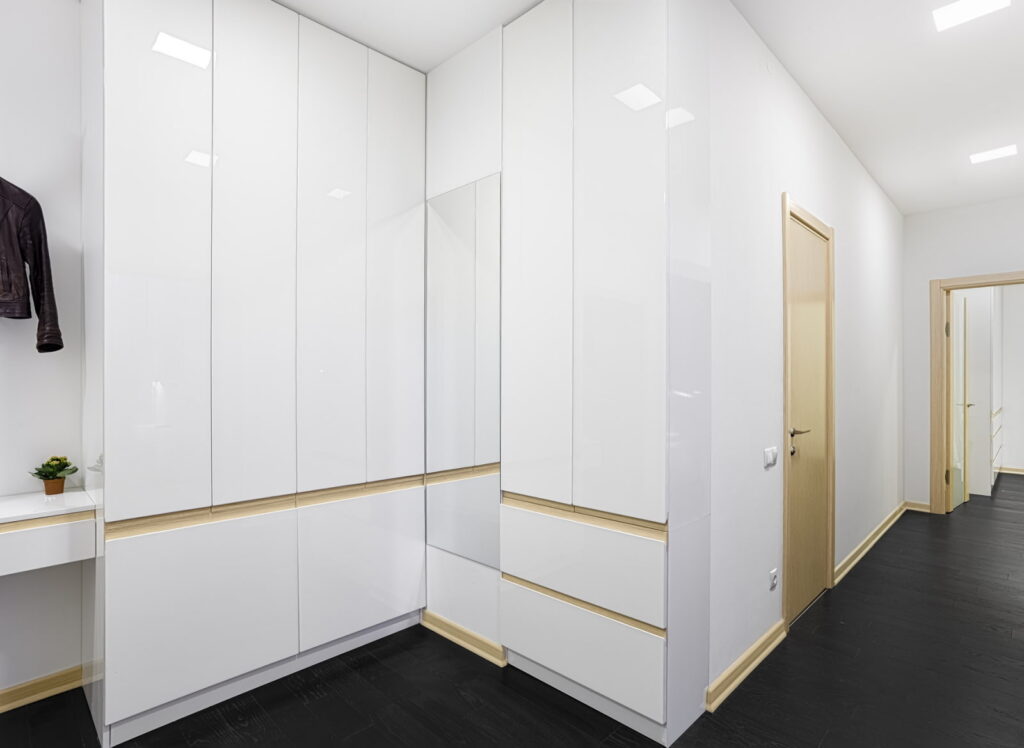 a hallway with white cabinets and black floors.