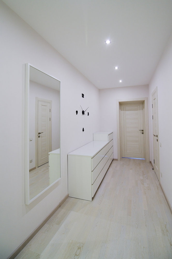 a hallway with white walls and a mirror.