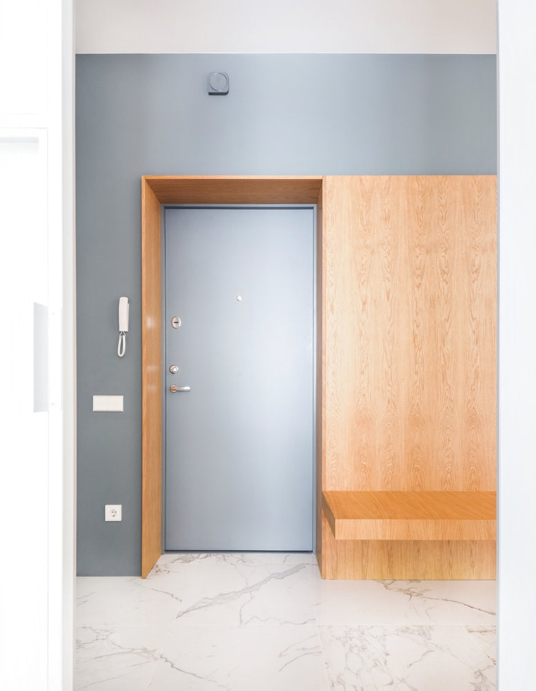 a hallway with a wooden door and a bench.