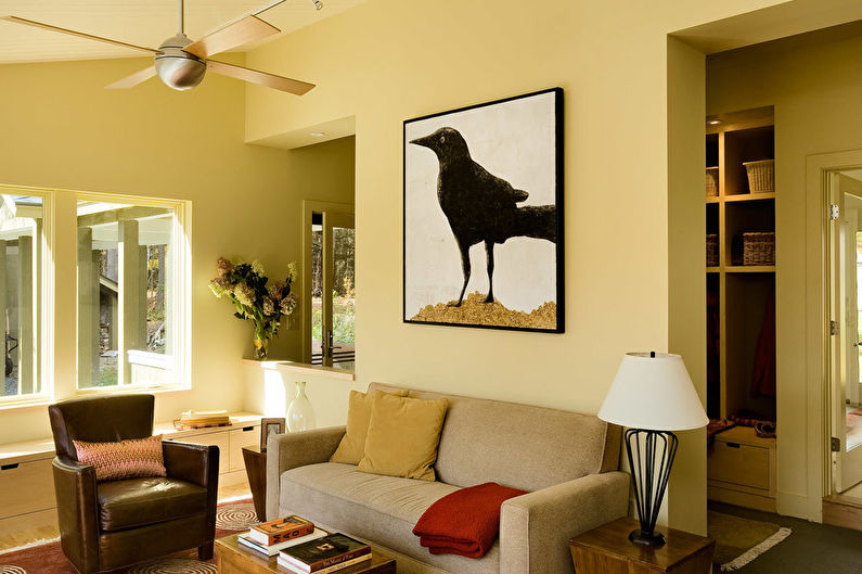 a living room with a brown couch and a crow on the wall.