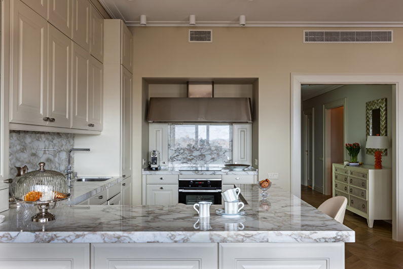 a kitchen with white cabinets and marble counter tops.