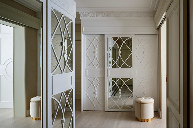 a hallway with white doors and mirrors.