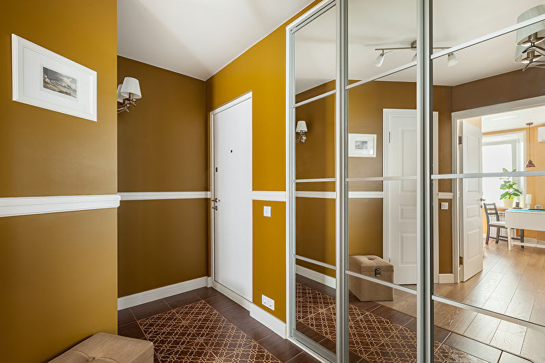 a hallway with yellow walls and a mirror.