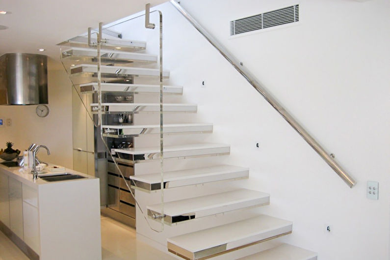 a white staircase in a kitchen with stainless steel railings.