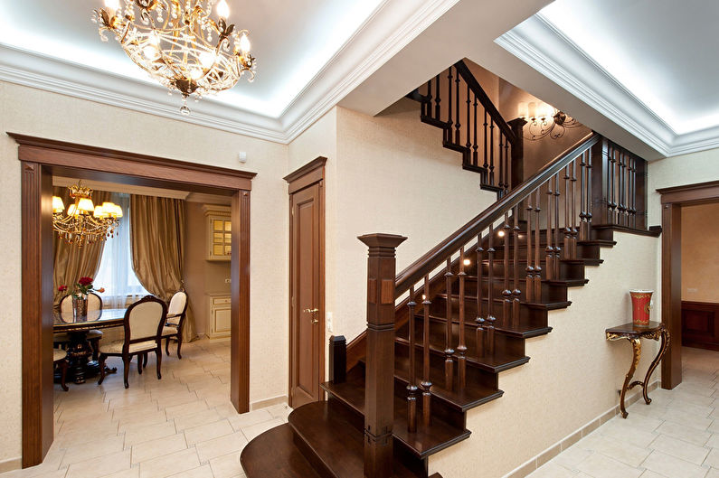 a hallway with wooden stairs and a chandelier.