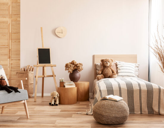 a child's room with a bed, chair and teddy bear.