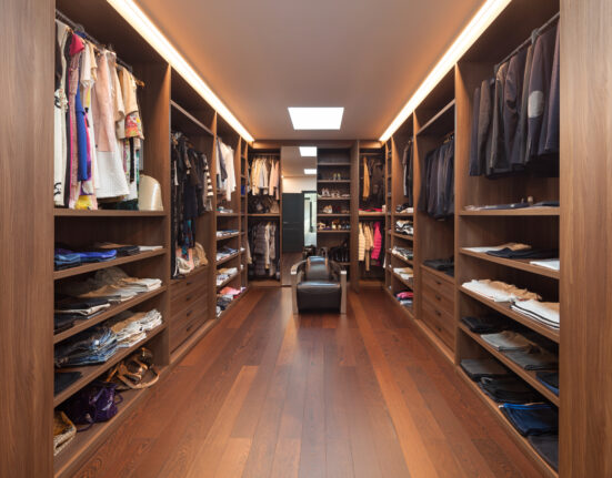 a walk - in closet with a wooden floor.
