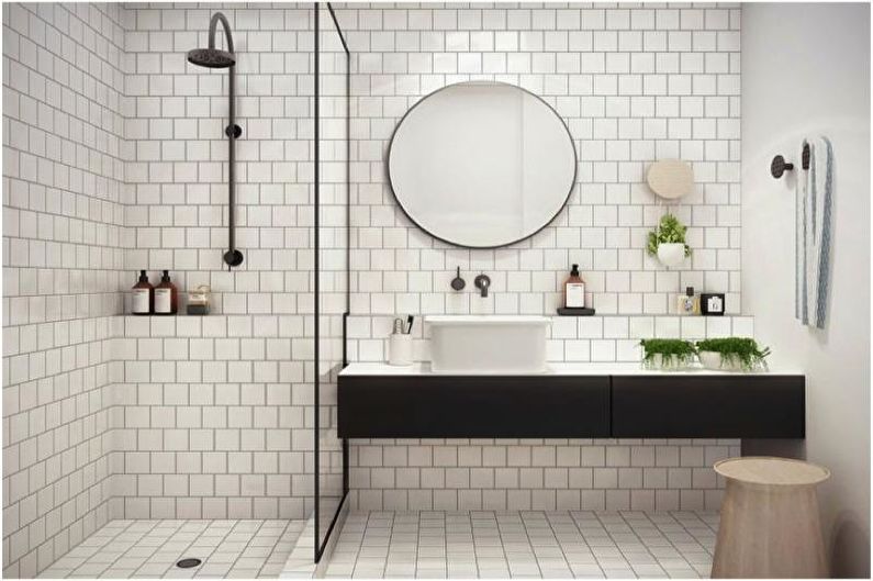 a white and black tiled bathroom with a round mirror.