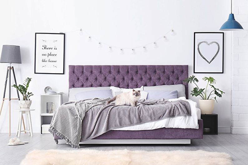 a purple upholstered bed in a bedroom with white walls.