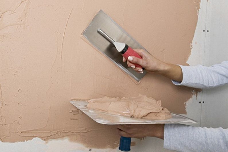 a woman is painting a wall with a brush.