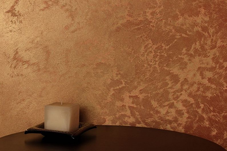 a candle sits on a table in front of a brown wall.