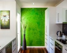 a kitchen with a green wall and white cabinets.