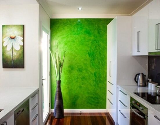 a kitchen with a green wall and white cabinets.