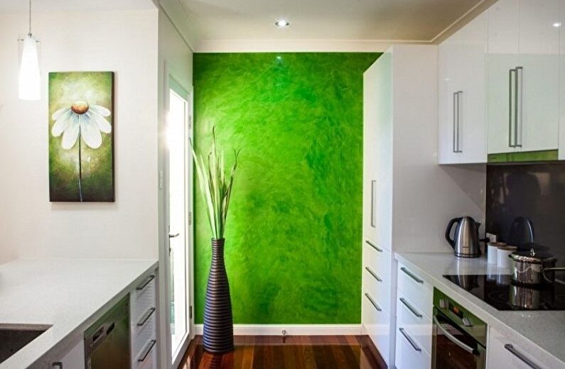 a kitchen with a green wall and white cabinets.