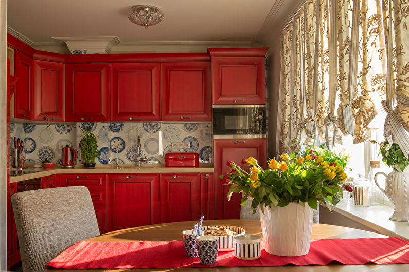 A kitchen with red cabinets and a table with flowers.