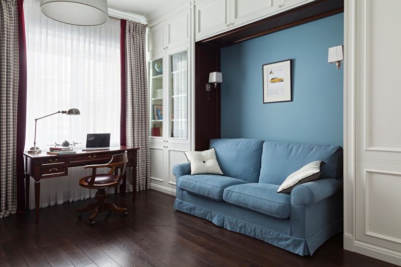 A room with a blue couch and a desk.