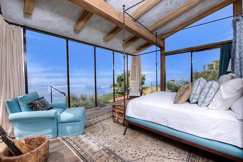 A bedroom with a large window overlooking the ocean.