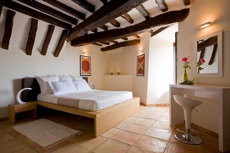 A bedroom with wooden beams and a white bed.