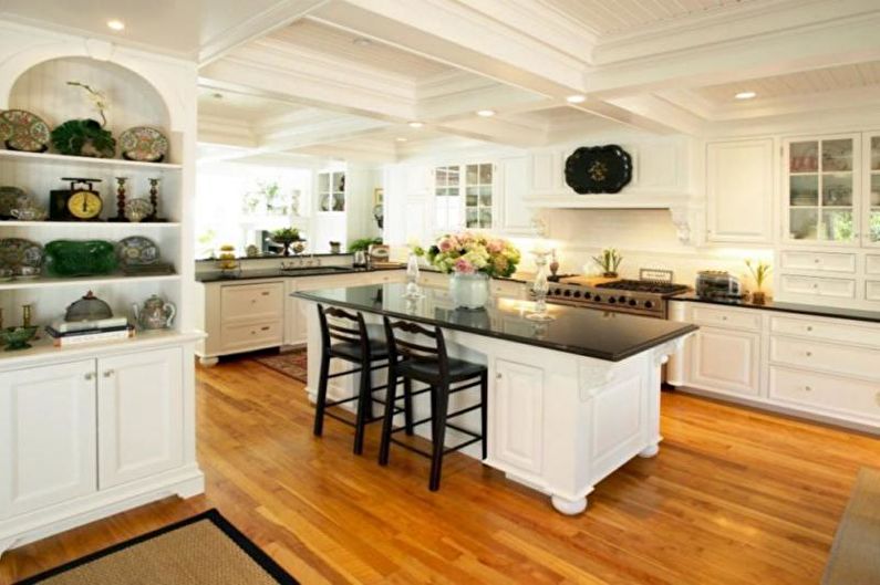 A kitchen with white cabinets and black counter tops.