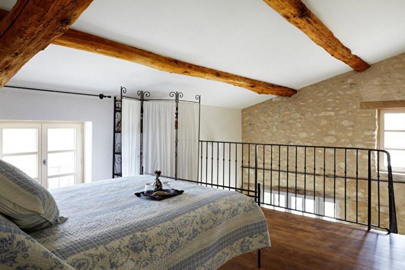 A bedroom with stone walls and wooden beams.