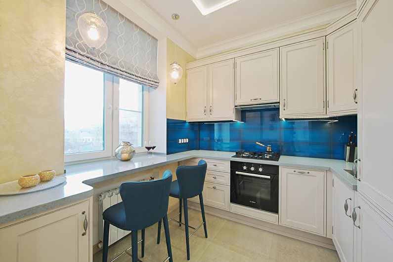 A kitchen with blue tiled walls and blue chairs.