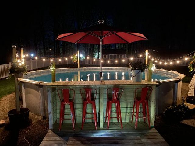 A pool bar with red stools and lights.