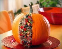 A pumpkin is sitting on a red plate with berries on it.