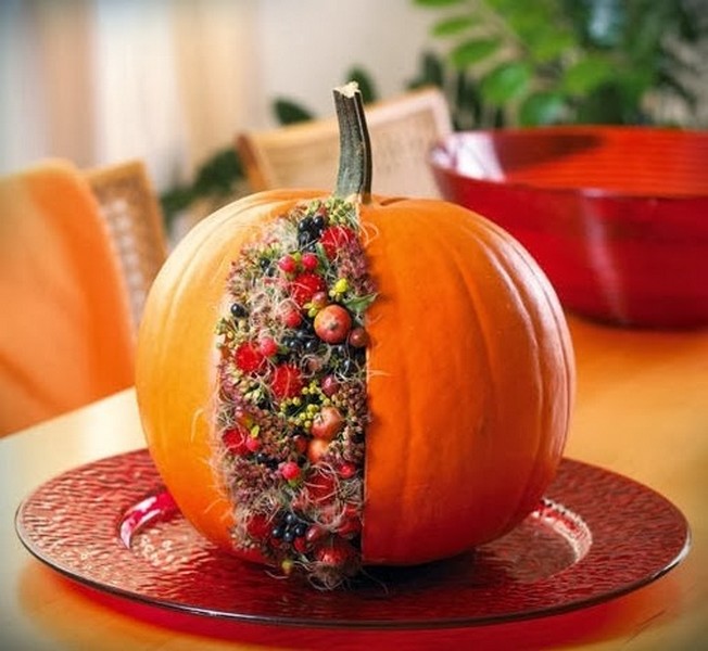 A pumpkin is sitting on a red plate with berries on it.