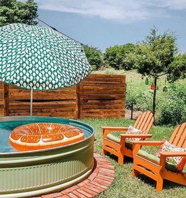 An outdoor pool with an umbrella and chairs.