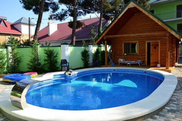 A swimming pool in front of a wooden house.