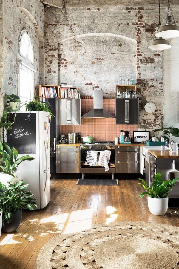 A kitchen with lots of plants and brick walls.