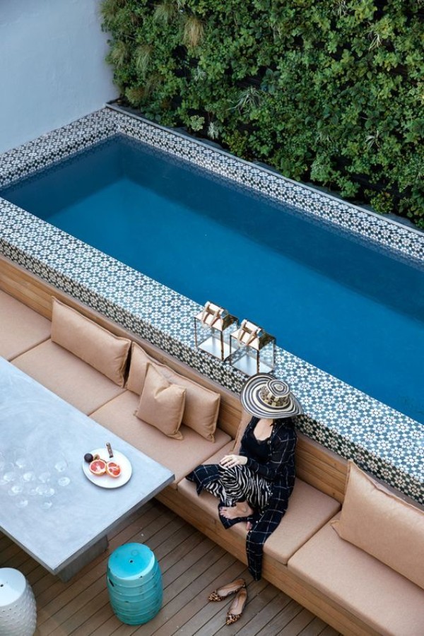 A woman sits on a couch next to a pool.