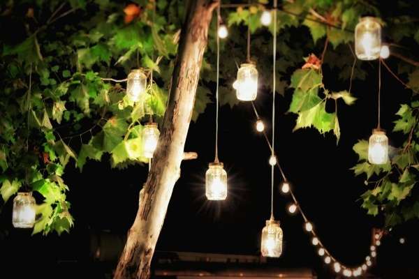 Mason jars hanging from a tree at night.