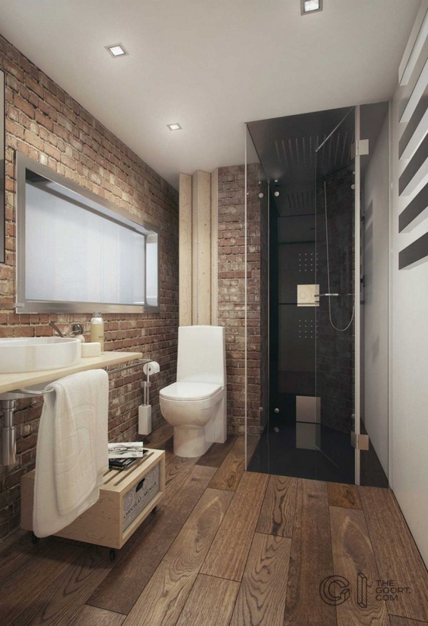 A bathroom with a brick wall and wooden floors.