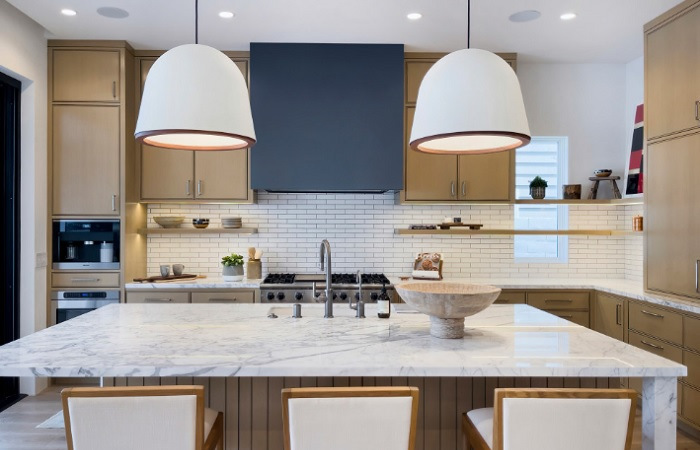 A modern kitchen with marble counter tops and stools.