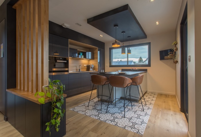 A kitchen with black cabinets and wooden floors.