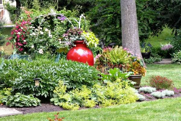 A garden with a red urn in the middle.