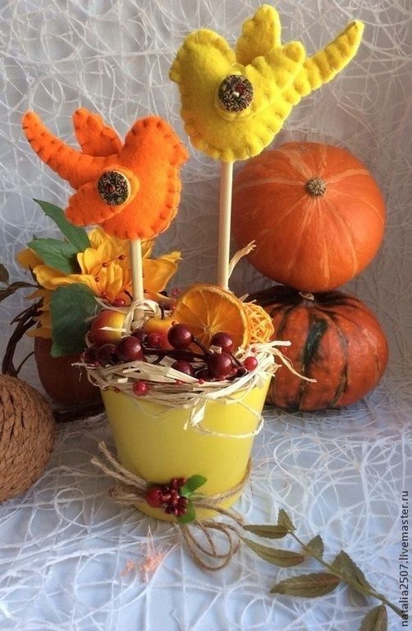 Two felt birds sitting in a yellow flower pot.